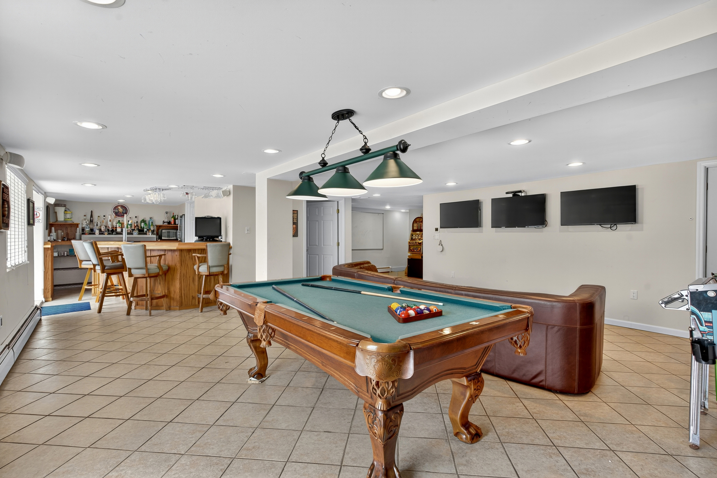 finished basement game room with pool table, bar and multiple TVs.